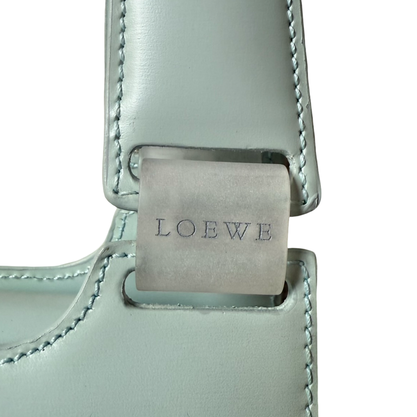 Close-up of a light blue leather strap with 'LOEWE' branding on a white background